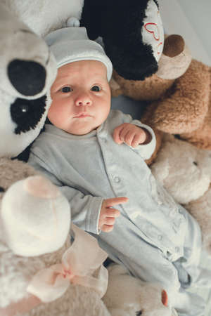 newborn baby laying with five teddy bears on blanketの写真素材