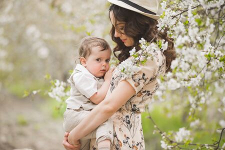 Beautiful young brunette in a colorful dress with her baby. Mother is breastfeeding her baby....