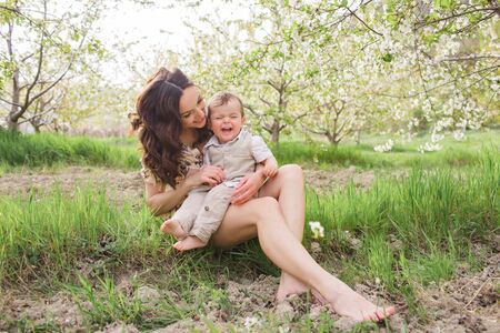 Beautiful young mom plays with her son in the spring garden. Holidays in the villageの写真素材
