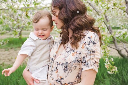 Beautiful young mom plays with her son in the spring garden. Holidays in the villageの写真素材