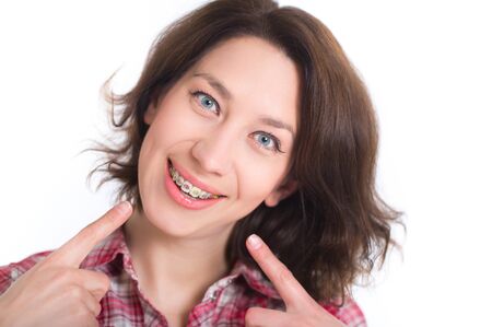 Beautiful girl with perfect skin and multi-colored braces posing on white backgroundの写真素材