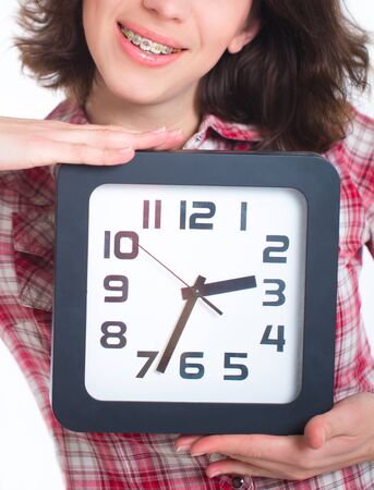 Girl in a plaid shirt with multi-colored braces holding a watchの写真素材