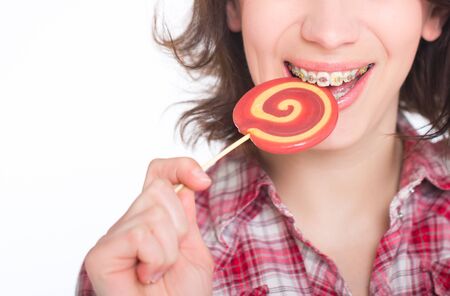 Close-up shot of girl with multicolored bracket systems and lollipopの写真素材