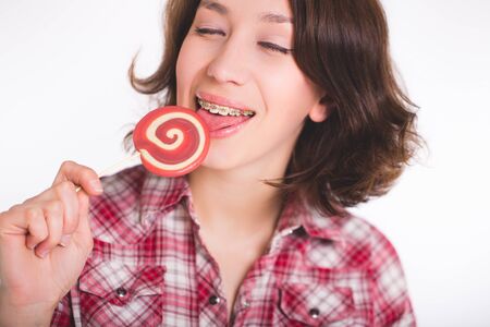 Close-up shot of girl with multicolored bracket systems and lollipopの写真素材