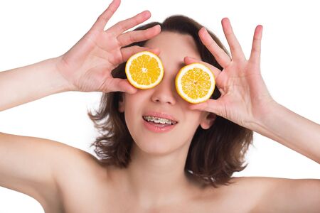 Beautiful girl with perfect skin and multi-colored braces posing with lemon on palmの写真素材