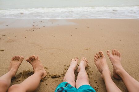 Baby legs view from above. Photo on the beach. A group of children sitting on the sand near the waterの写真素材