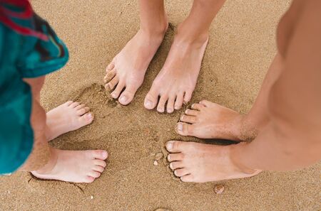 Baby legs view from above. Photo on the beach. A group of children sitting on the sand near the waterの写真素材