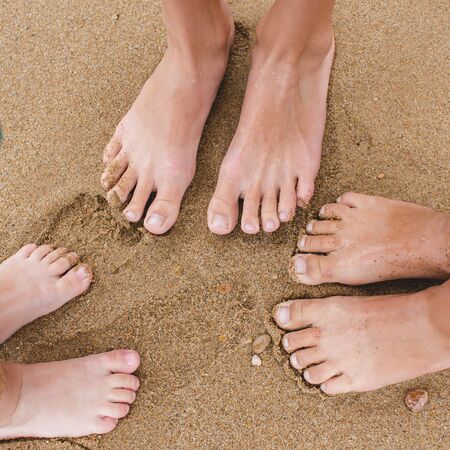 Baby legs view from above. Photo on the beach. A group of children sitting on the sand near the waterの写真素材