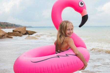 A girl is playing on the beach with an inflatable flamingo. the hit of the seasonの写真素材