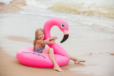 A girl is playing on the beach with an inflatable flamingo. the hit of the seasonの写真素材
