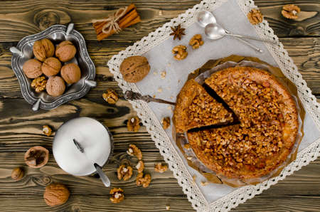 Piece of apple pie with walnut and sugar glaze on a wooden tableの写真素材