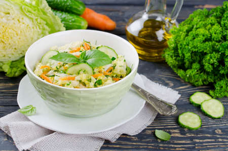 Cabbage salad with cucumber and carrots. Salad and vegetables on wooden tableの写真素材