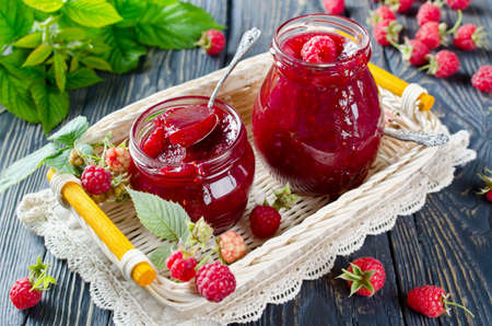 Raspberry jam ( marmalade ) and fresh raspberry on a rustic wooden table.Selective focus