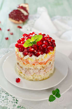 Layered salad from vegetables on the holiday table. Salad with walnuts, cheese, pomegranate and vegetablesの写真素材
