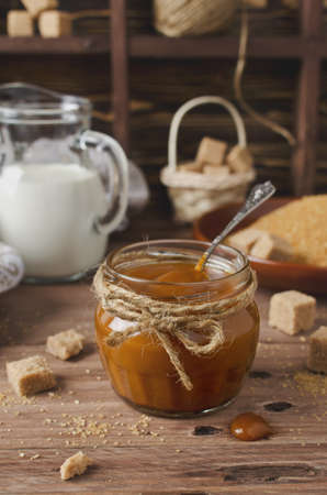 Homemade caramel sauce and ingredients on wooden table. Brown sugar, cream, butterの写真素材