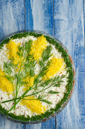Salad with sardines Mimosas on a blue wooden background. Salad decorated with sprigs of Mimosaの写真素材