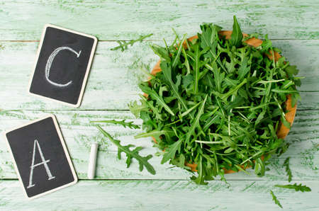 Fresh green arugula in bowl on wooden table. Arugula is rich in vitamins and trace elementsの写真素材