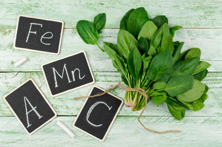 Fresh bunch of spinach on a wooden background. Spinach is rich in vitamin C, A, manganese and iron