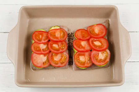 Cooking oven baked fish fillet with zucchini and tomatoes under a cheese crust. Step-by-step cookingの写真素材