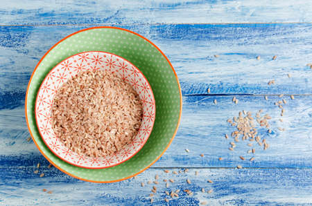 Red short-grain rice in a bowl on a blue wooden background. Top view