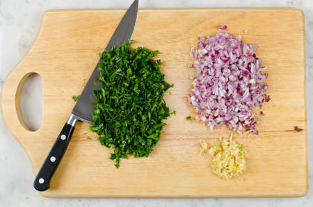 Chopping of onion, garlic and fresh herbs. Step by step cookingの写真素材