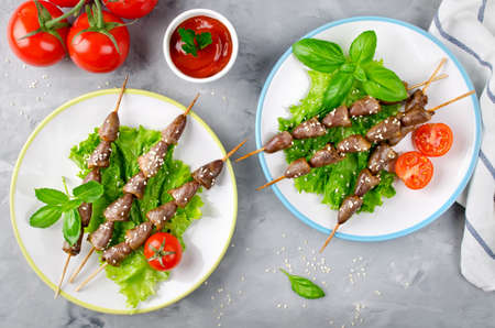 Chicken hearts on a barbecue sticks topped with sesame seeds served on a grey concrete background. Barbecue lunchの写真素材