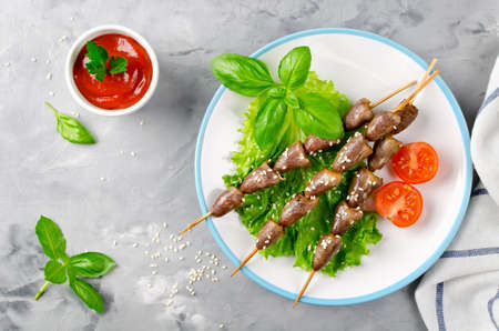 Chicken hearts on a barbecue sticks topped with sesame seeds served on a grey concrete background. Barbecue lunchの写真素材