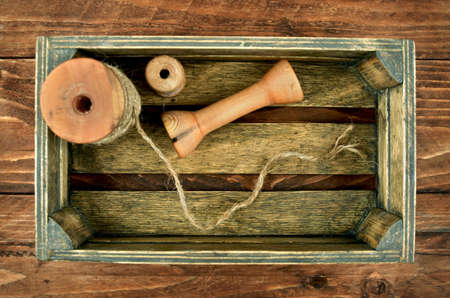 Vintage box with bobbins, reels, spools, threads and lace. Small box of tools in wooden workshop