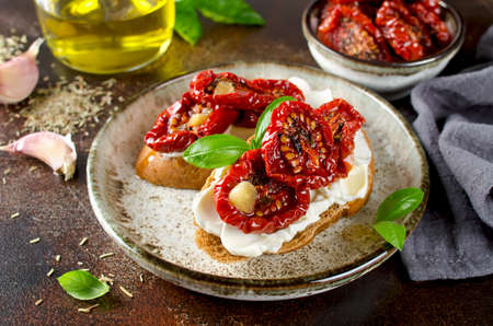 Bruschetta with olive oil, sundried tomatoes, cottage cheese and fresh basil. Tasty savory Italian appetizersの写真素材