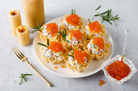 Tartlets with crab sticks, eggs, corn, poppy seeds and caviar. Cold portioned appetizer.の写真素材