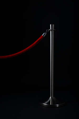 silver stanchion with a red rope, isolated on blackの写真素材