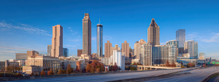 Panoramic view of a city skyline with various skyscrapers against a clear blue skyの素材