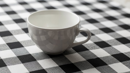 Coffee cup on black and white checkered tableclothの素材