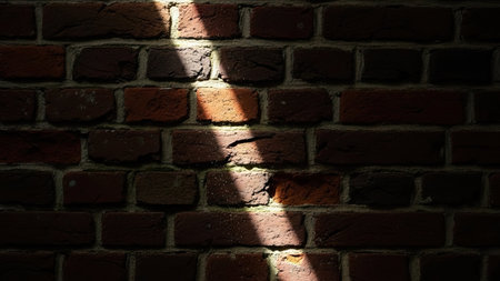 Brick wall with sunbeam and shadow in the darkness. Abstract background.の素材