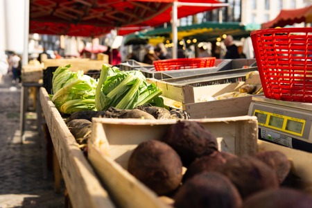 Market scene greens and root vegetables sitting on tables with scales and baskets farmers market franceの写真素材