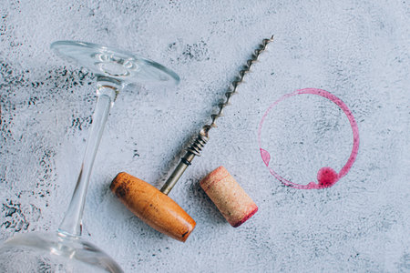 Top view of vintage corkscrew, cork, wineglass and red wine stain or ring over gray backgroundの写真素材
