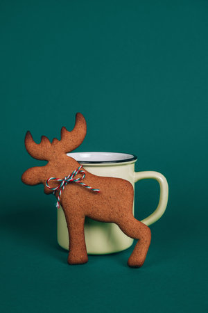 Christmas homemade gingerbread deer cookie with yellow cup of tea on green background. Christmas or New Year winter holiday concept.の写真素材