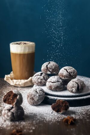 A few marble brown cookies with glass of coffee latte, star anise and powdered sugar on wooden backgroundの写真素材