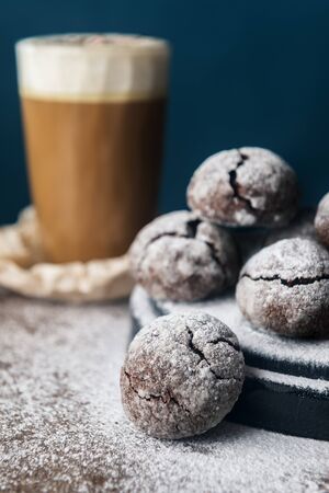 A few marble brown cookies with glass of coffee latte, star anise and powdered sugar on wooden backgroundの写真素材