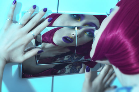 Close-up face of the pretty fashion girl with purple lips and pink hair with bathroom background