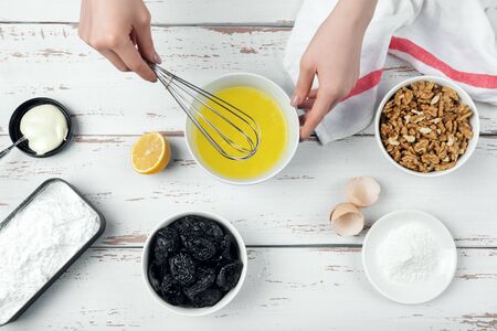 Ingredients for merengue roll cooking. Human hands beat egg whites. Baking or cooking white wooden background. Top view.の写真素材