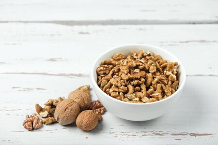 Whole and peeled walnuts on white colored old vintage wooden backdrop. Grunge wood background.の写真素材