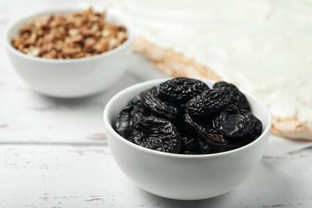 Prunes, walnuts and meringue cake on white colored old vintage wooden backdrop. Grunge wood background.の写真素材