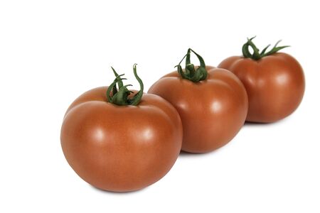 Three red tomatoes in a line on a white backgroundの写真素材