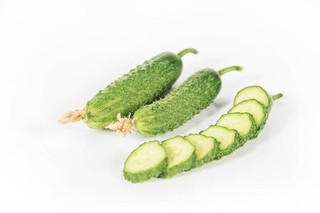 Fresh green pickling cucumbers with slices and isolated on white backgroundの写真素材