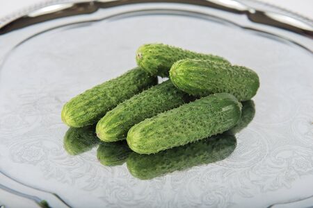 Group of fresh green pickling cucumbers on metal tray with folk ornamentの写真素材