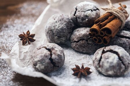 A few marble brown cookies with star anise, cinnamon and powdered sugar on parchment backdropの写真素材