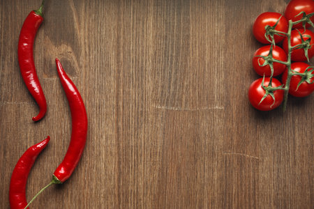Red ripe fruits of chili pepper and cherry tomato on a wooden tableの写真素材