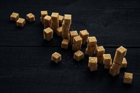 Pieces of brown cane sugar on the black wooden tableの写真素材