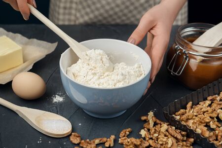 Woman in checkered apron cooking tart. Cook mixing ingredients for cooking tart, cookies, and bakery. の写真素材